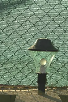 Category Historic EN Prints: Lampshade against crossed mesh and green cloth at holiday resort