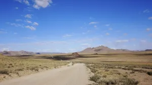 Landscape of outdoor road in wild field with mountains at horizon