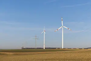 Landscape with wind turbines and power lines in front of a blue sky