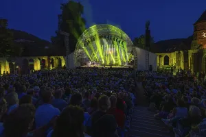 A large crowd enjoys an open-air concert with impressive stage lighting