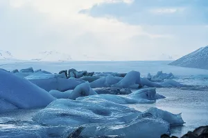 Large icebergs in a serene ocean setting under a dramatic sky with blue tones