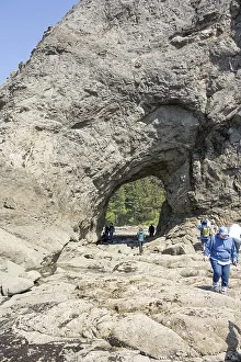 Large rock with a hole and people in the foreground
