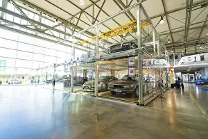 Large room with glass garage and several cars