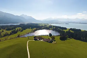 Large-scale view of hilly, wooded landscape with Hegratsried Lake and mountains