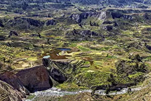 Large-scale view of terraced fields in a vast mountain landscape with a river