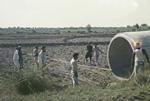 A large section of drainage pipe is positioned for an irrigation project in rural Pakistan in 1962