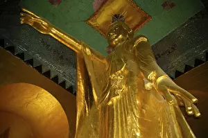 Large standing golden Buddha statue with outstreched arm and pointing finger