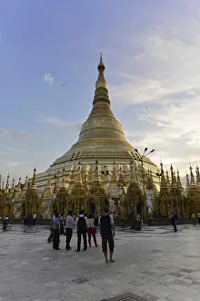 A large stupa rises at sunset on a busy temple square