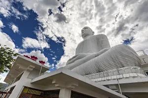 Framed Print : Large white Buddha statue under dramatic sky surrounded by temple architecture and clouds Framed Print : Large white Buddha statue under dramatic sky surrounded by temple architecture and clouds