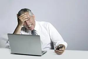 Laughing senior businessman computer phone hand gesture on head