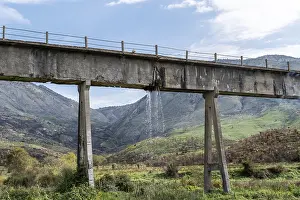 Leaky aqueduct with waterfall against mountain backdrop