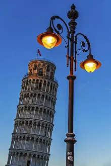 The Leaning Tower under an illuminated street lamp in the evening light