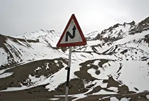 Left reverse bend signboard with Himalayan mountain