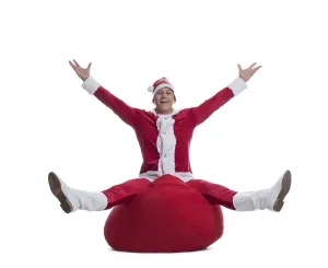 Full length portrait of happy young Santa sitting on bag