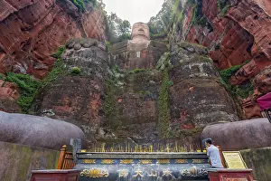 Leshan, China - July 2019 : Chinese male pilgrim lightening memorial candles at the bottom of The Giant Leshan Buddha