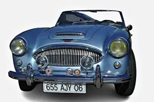 Light blue Austin Healey 3000 with open roof parked with white background
