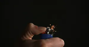 Lighter in Hand with Flame against Black background