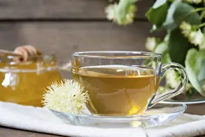 Linden tea in glass cup and jar with honey with linden flowers on a dark wooden background