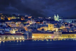 Lisbon historic old town with vibrant city lights under dramatic night sky