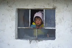 Little child looking out of a window near Cusco