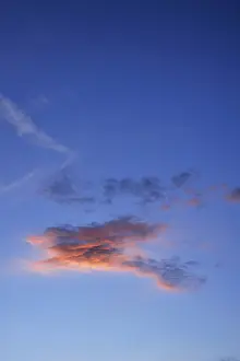 Little cloud against blue sky, lit by the setting sun