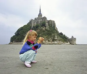 Little girl, age 7, examines what she found on the seabed in front of Mont Saint Michel