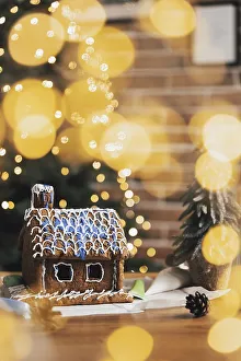 Little homemade gingerbread house with glaze standing on the table with decorations