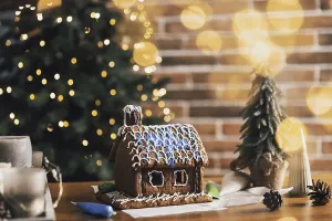 Little homemade gingerbread house standing on table with decorations