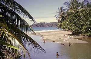 Local children swimming by beach in tidal river at the coast, island of Tobago, 1963