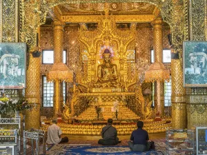 Locals praying, gilded sitting Buddha