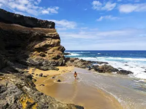 From above a lone woman walks on the sandy shore of Tindaya Beach in Fuerteventura