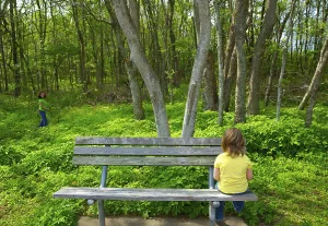 Lonely children sad looking the forest girl sitting at the park bench