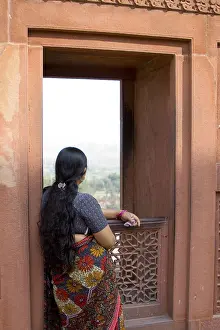 A long hair lady looking outside from the red fort window of Agra