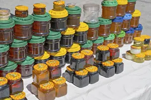 Lots of colorful honey jars with various lids on a market stand