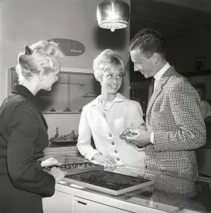 Love in the 1950s. A young couple at a jewelry shop is selecting wedding rings