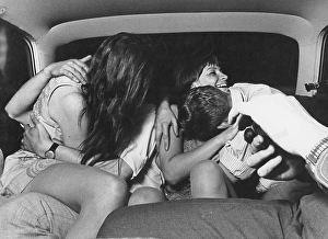 Love in the 1960s. Two couples are sitting in the back seat of the car kissing and hugging each other