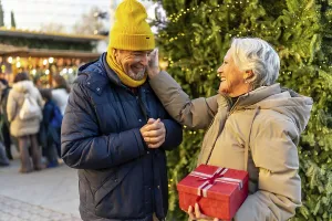 Loving senior couple exchanging christmas gifts at a traditional christmas market