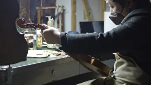 A luthier meticulously working on a violin in a well-equipped workshop