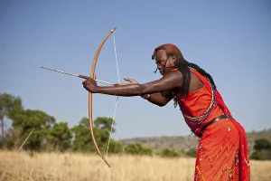 Faces Of The World Prints: Maasai warrior wearing traditional dress while doing archery with a bow and arrow