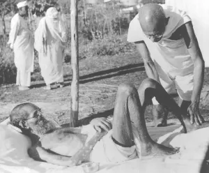 Mahatma Gandhi giving massage to a leper patient at Sevagram Ashram, 1940
