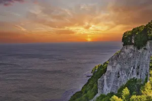Majestic view of cliffs on a coast with a glowing sunset in the background