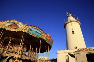 Malaga, lighthouse and old traditional carousel on the harbour promenade Muelleuno