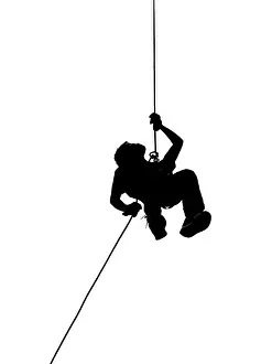 A male climber rappels downward on a rope