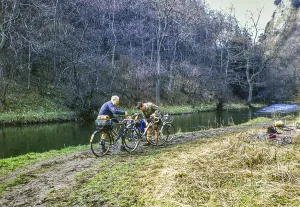 Two male cyclists tending to their bicycles on a muddy path by the River Dove, Dovedale, Peak District National Park, Derbyshire, England, Great Britain 1956