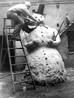Man adorns big snowman, ca. 1955