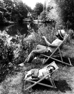 Man angling, dog in deck chair