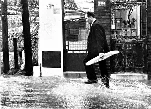 Man carrying a baguette through a flooded street