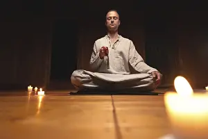 A man in clothes for practice and meditation sits in a lotus pose