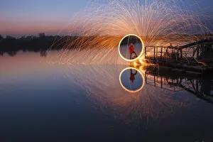 Man creates circle of light from steel wool over lake at night with reflection