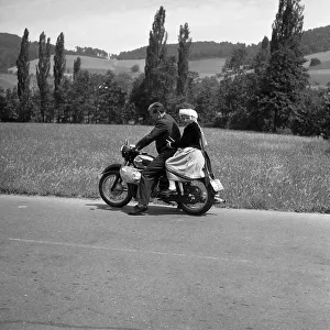 Man and daughter riding a motorbike on a country road